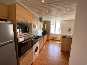 a kitchen with wooden cabinets and a washer and dryer at Le logis des Halles in Cerizay