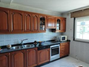 uma cozinha com armários de madeira, um lavatório e um micro-ondas em Casa Fina em Foz