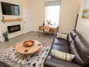 a living room with a leather couch and a table at Stone's Throw in Morpeth