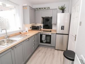 a kitchen with gray cabinets and a white refrigerator at Stone's Throw in Morpeth