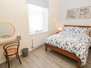 a bedroom with a bed and a mirror and a chair at Stone's Throw in Morpeth