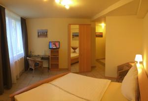 ein Hotelzimmer mit einem Bett, einem Schreibtisch und einem Schlafzimmer in der Unterkunft Hotel Reesenhof in Witten