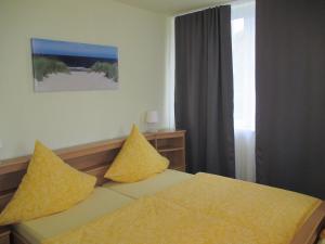a bedroom with a bed with yellow pillows and a window at Hotel Reesenhof in Witten
