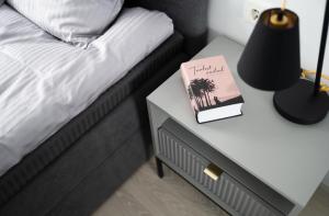 a bed with a table with a book on top of it at Pärnu Verde Apartments in Pärnu