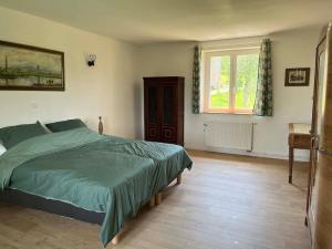 Un dormitorio con una cama verde y una ventana en Maison vue superbe, 1-6 pers, Teilhet, Auvergne, en Teilhet