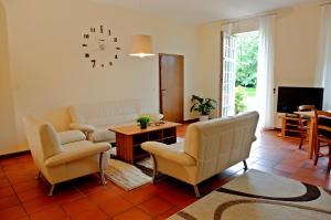 a living room with a couch and chairs and a clock at Ferienwohnung Art Land in Badbergen