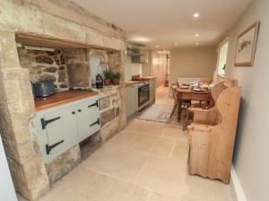 a large kitchen with a stone wall and a table at Harnham Hall Cottage in Newcastle upon Tyne