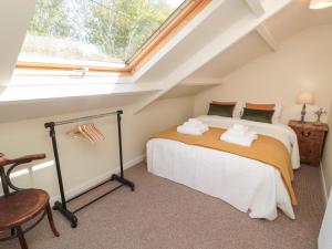 a attic bedroom with two beds and a window at Harnham Hall Cottage in Newcastle upon Tyne