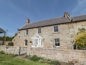 an old stone house with a stone wall at Harnham Hall Cottage in Newcastle upon Tyne