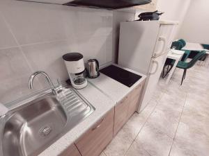 Una pequeña cocina con fregadero y refrigerador. en Emerald home, en Ixia