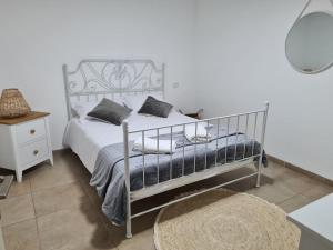 1 dormitorio con 1 cama blanca con marco metálico en חלומות סיגלית בקריית שמונה, en Kiryat Shemona