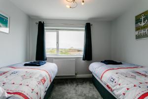 two beds in a room with a window at Island View in Amble