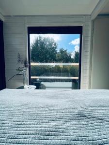 a bedroom with a bed and a large window at Waterview - Schwimmendes Ferienhaus auf dem Wasser mit Blick zur Havel, inkl Motorboot zur Nutzung in Fürstenberg-Havel