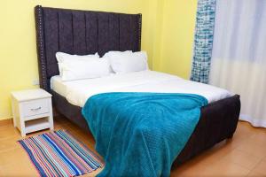 een bed met een blauwe deken erop in een kamer bij Cosy One bedroom Thika Road,TRM in Nairobi