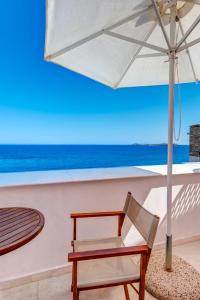 a chair and an umbrella in front of the ocean at Apollonion Palace in Ermoupoli