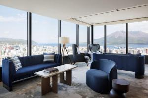 a living room with blue furniture and a view of a city at Sheraton Kagoshima in Kagoshima