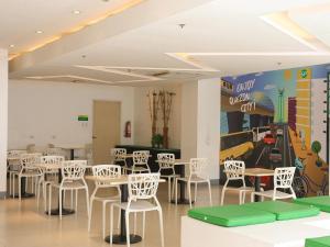 a dining room with white chairs and tables and a bowling alley at Go Hotels North EDSA in Manila