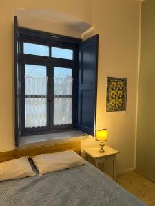 Dormitorio con ventana, cama y lámpara en Almira Studios and Apartments, en Agia Marina