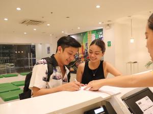 馬尼拉的住宿－Go Hotels Timog，男人和女人在柜台上写文章