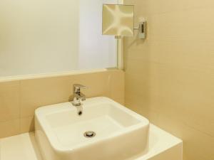 Go Hotels Timog في مانيلا: بالوعة بيضاء في الحمام مع نافذة
