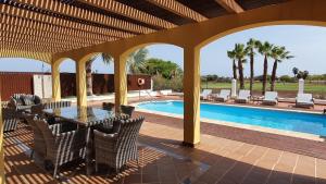 patio ze stołem i krzesłami oraz basenem w obiekcie Villa BONITA on Golf in El Descanso ,Caleta Fuste-Fuerteventura w mieście Caleta De Fuste