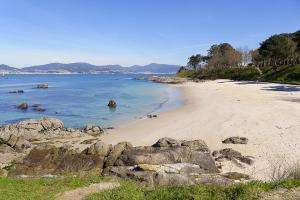 einen Strand mit Felsen und dem Meer an einem sonnigen Tag in der Unterkunft Alójate en el corazón de Vigo in Vigo