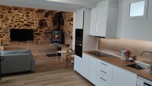 a kitchen and living room with a stone wall at CASA DO PENEDO in Camariñas