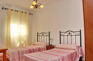 2 łóżka w pokoju z biało-różową pościelą w obiekcie Apartamento Añil w mieście Conil de la Frontera