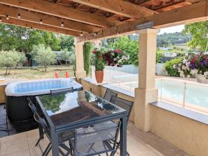 un tavolo in vetro su un patio con piscina di Villa en Provence avec piscine et jacuzzi a Tavernes