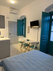 1 dormitorio con puerta azul, mesa y sillas en Almira Studios and Apartments, en Agia Marina