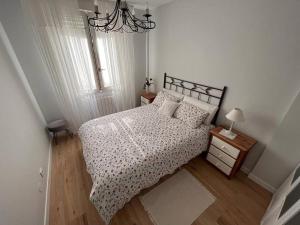 a small bedroom with a bed and a chandelier at Los Girasoles in Comillas