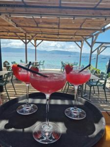tre cocktail su un tavolo con l'oceano sullo sfondo di Hotel L'Escale a Porto Pollo