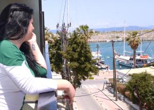 a woman sitting on a balcony looking at the water at Veroniki Hotel in Kos