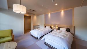 una camera d'albergo con due letti e una sedia di Nakamatsuya Ryokan a Ueda