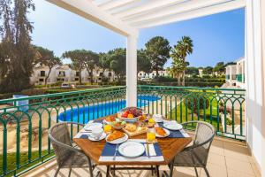 a table with food on a balcony with a view of a pool at Pine Cliff Apartment by The Portuguese Butler in Olhos de Água