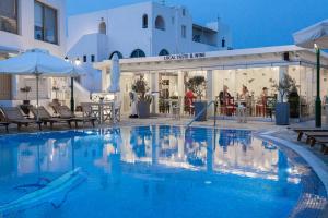 a swimming pool in a hotel with tables and umbrellas at Hotel Mathios in Akrotiri