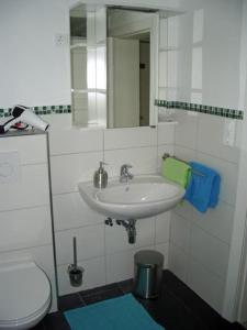 bagno con lavandino, servizi igienici e specchio di Ferienhaus Strobel a Bardowick