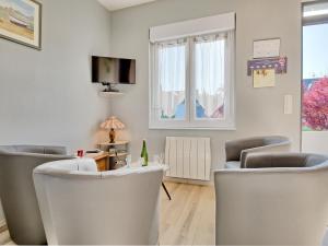 a living room with two white chairs and a tv at Holiday Home La Corvette by Interhome in Pléneuf-Val-André