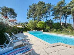 a swimming pool with two lounge chairs next to a house at Holiday Home Eden Parc by Interhome in Lacanau-Océan