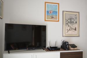 uma grande televisão de ecrã plano sentada numa parede branca em Appartamento Climatizzato con Piscina Ca' Aurelia em Lido di Savio