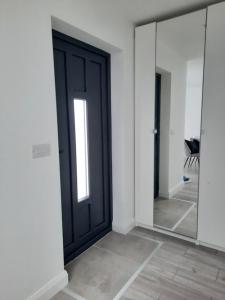 een zwarte deur in een witte kamer met spiegels bij Guest house in Dublin in Cluain Aodha