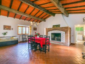 a dining room with a red table and chairs and a fireplace at Apartment Fattoria Petraglia - Padronale by Interhome in Monteriggioni