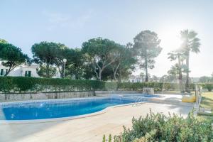a swimming pool in a yard with trees at Pine Cliff Apartment by The Portuguese Butler in Olhos de Água