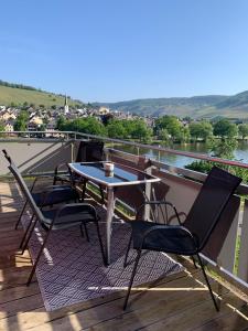 a table and chairs on a deck with a view of a river at Moselflair in Bernkastel-Kues