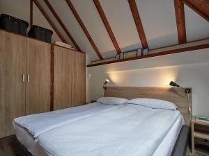 um quarto com uma grande cama branca e armários de madeira em Holiday Home Am Sternberg 4 by Interhome em Frankenau
