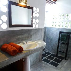 ein Bad mit einem Waschbecken und einem Spiegel in der Unterkunft East Surf Cabanas in Arugam Bay