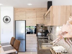 a kitchen with wooden cabinets and a stainless steel refrigerator at Apartment Sant Maurici-22 by Interhome in Empuriabrava