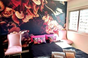 プラヤ・パライソにあるLuxury Kim Apartment, Ocean View & Wifi Freeの花の壁のベッドルーム(ピンクの椅子付)