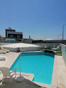 une grande piscine avec un parasol et des chaises dans l'établissement House of PAB, à Praia da Areia Branca