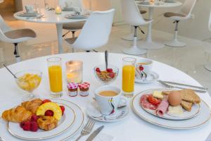 a table topped with plates of breakfast foods and orange juice at Hôtel d'Angleterre Rouen Centre Gare in Rouen